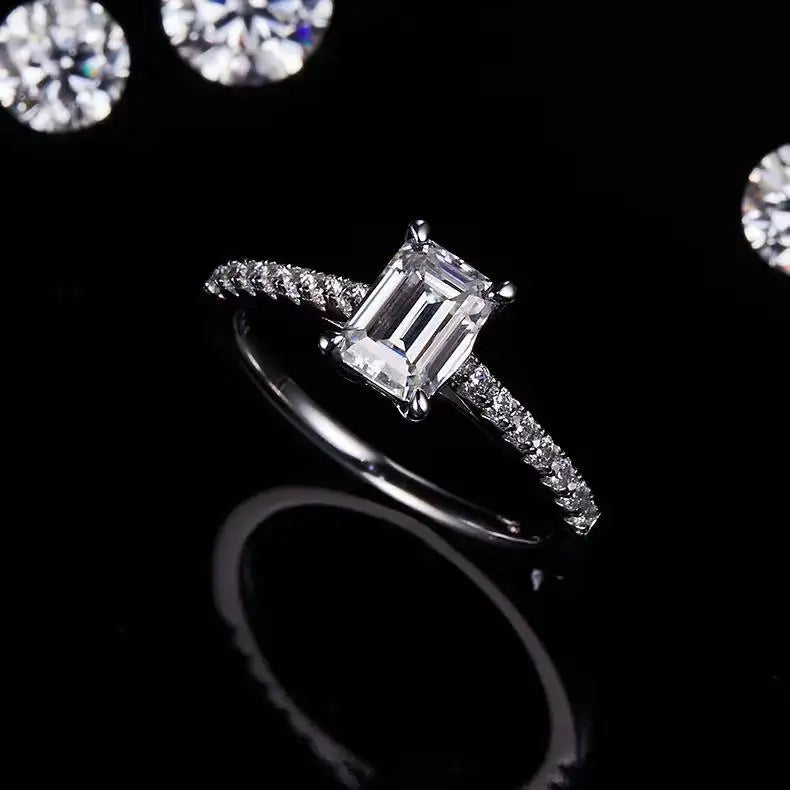 A sophisticated engagement ring with a 1.00ct emerald cut moissanite, presented in a low-profile basket setting.