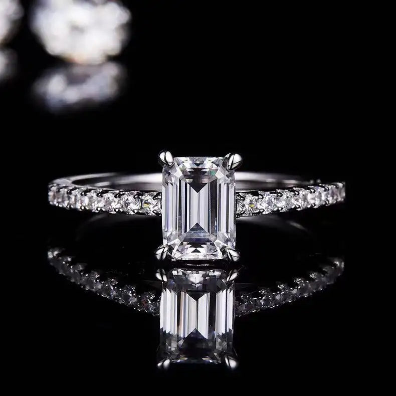 A close-up view of a 1.00ct emerald cut moissanite in a carefully crafted basket setting, emphasizing its facets and sparkle.
