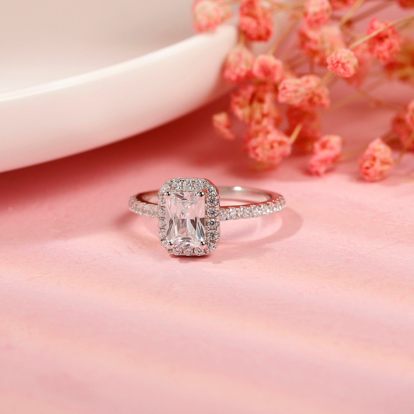 This beautiful ring showcases a brilliant 1.00ct emerald cut moissanite as its centerpiece, enhanced by a delicate halo, all crafted in fine sterling silver.