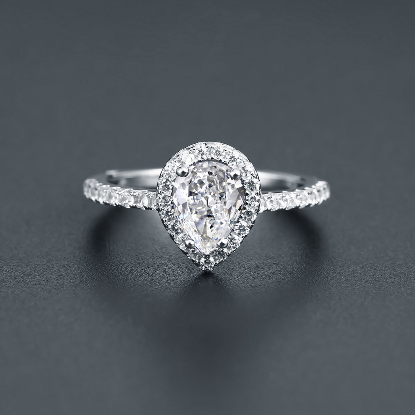 This ring showcases a brilliant 1.25ct pear-cut moissanite embraced by a halo of stones, set in polished sterling silver.