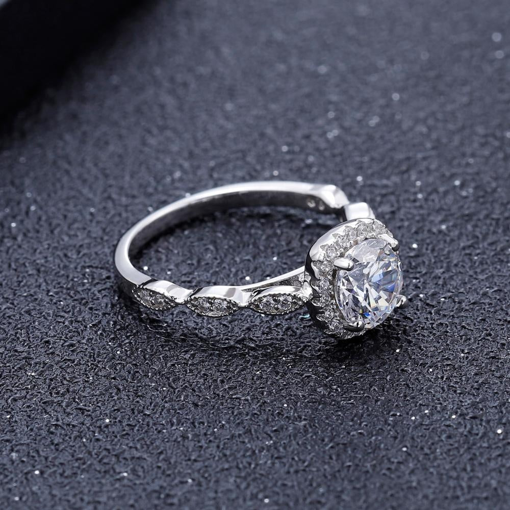 A stunning 1.00ct moissanite takes center stage in this sterling silver ring, featuring a vintage halo and ornate detailing.