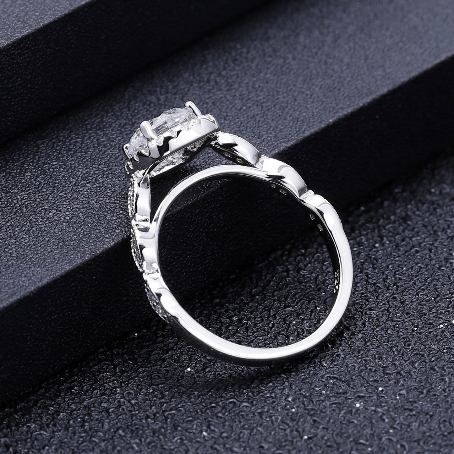 This engagement ring features a 1.00ct moissanite nestled within a vintage-style halo, showcasing intricate sterling silver craftsmanship and a timeless design.