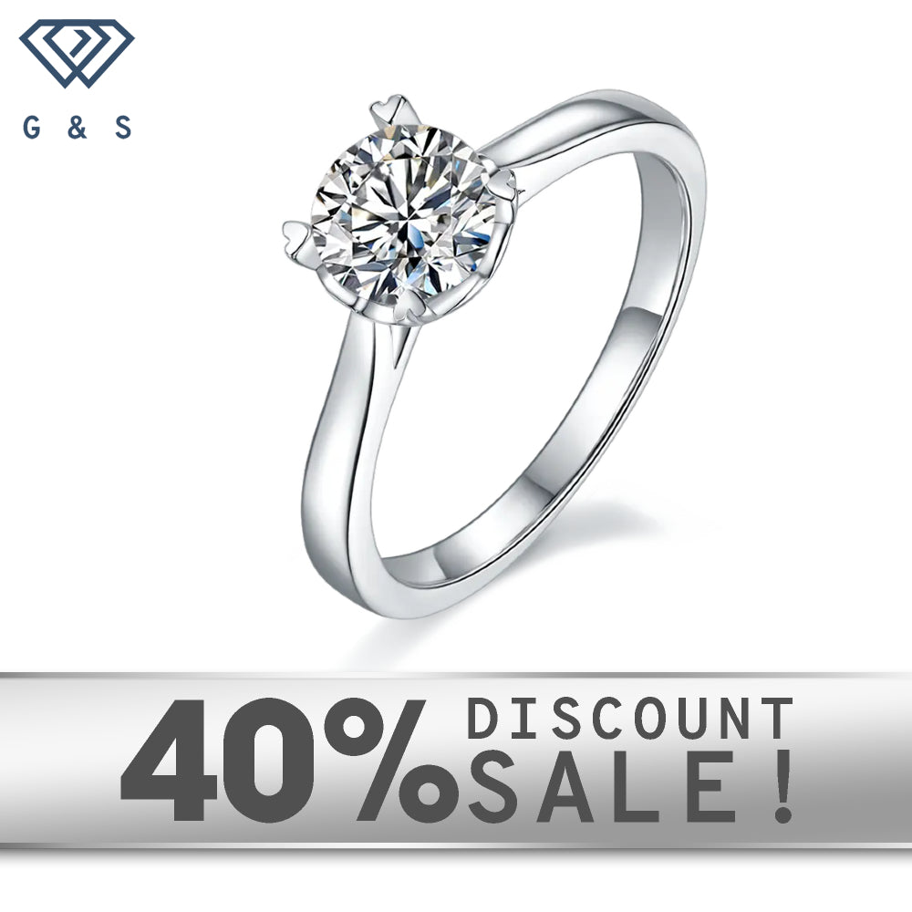 A 1.00ct moissanite sparkles in a timeless 4-prong setting with heart-shaped claws, crafted in 9ct white gold.