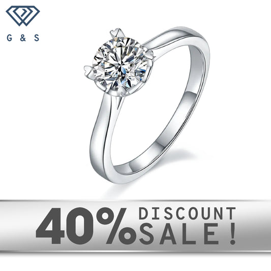 A 1.00ct moissanite sparkles in a timeless 4-prong setting with heart-shaped claws, crafted in 9ct white gold.