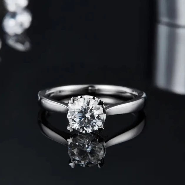 A 1.00ct moissanite takes center stage in this unique 4-prong setting with heart-shaped claws, crafted in 9ct white gold.