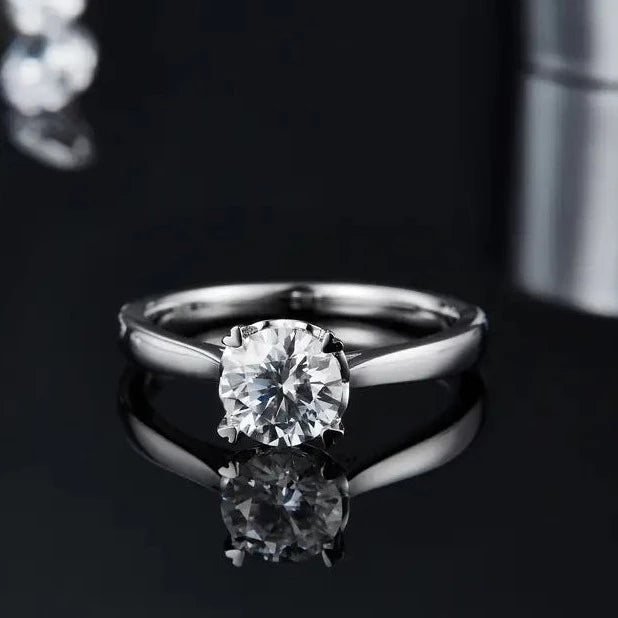 A close-up view of a sterling silver engagement ring showcasing a 1.00ct moissanite held securely by intricately designed heart-shaped claws.