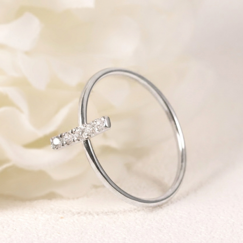 Silver ring with small diamonds on a soft white fabric background