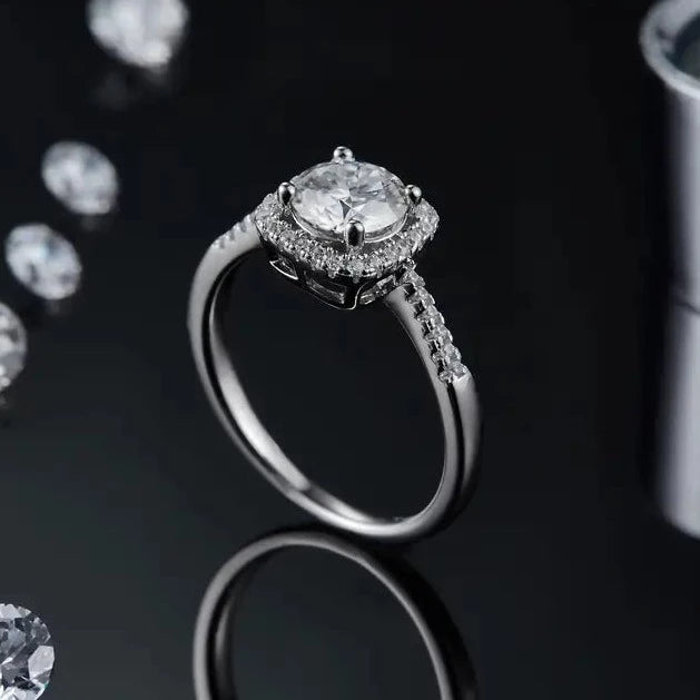 A sophisticated engagement ring featuring a 1.00ct moissanite center stone with a halo design, presented in polished sterling silver.