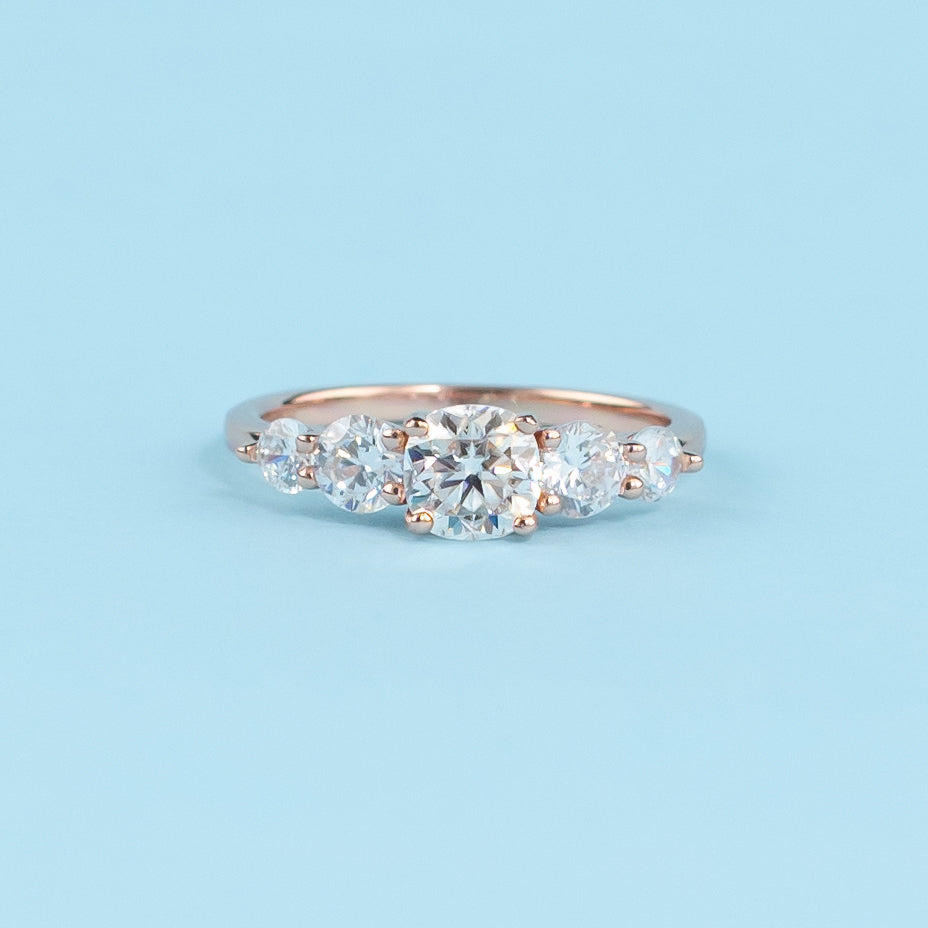 Stunning five-stone engagement ring with cushion cut moissanites, set in warm 9ct rose gold for eternal brilliance.