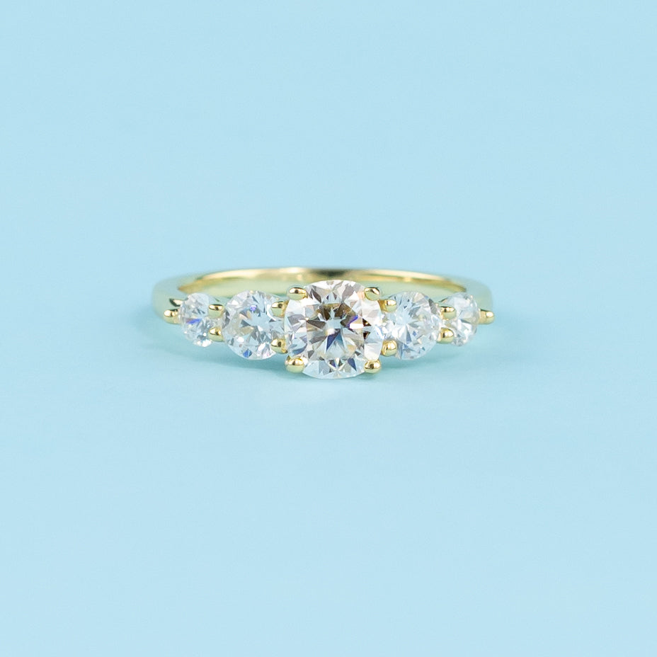 This elegant ring showcases five sparkling cushion cut moissanites, representing a lifetime of brilliance.