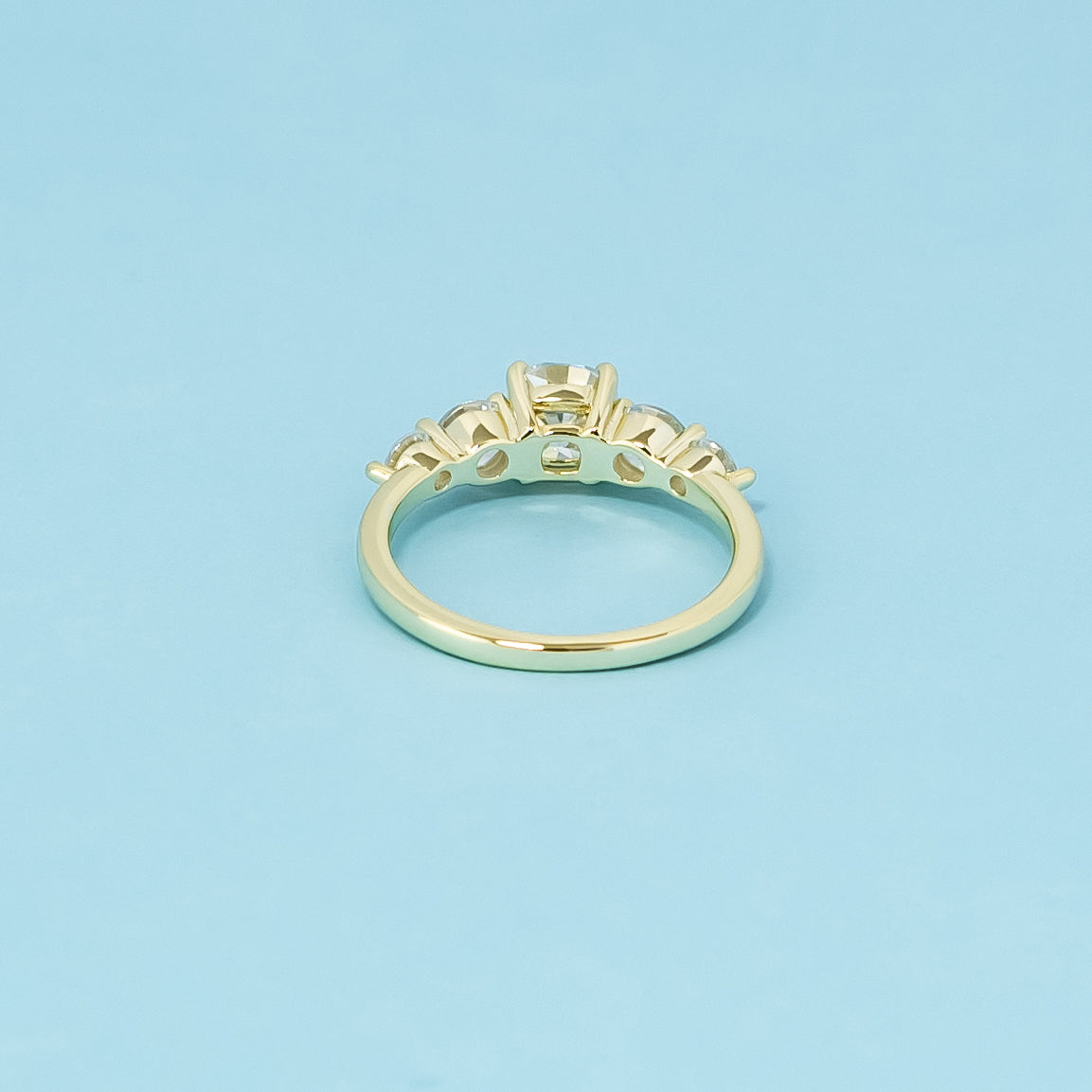 This 9ct yellow gold engagement ring features five brilliant cushion cut moissanites, representing everlasting elegance.