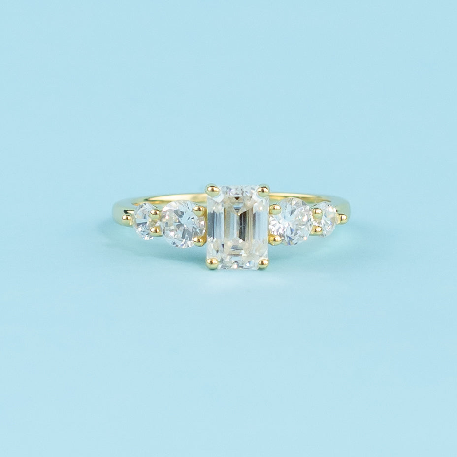This ring showcases five sparkling emerald cut moissanites, representing a lifetime of brilliance.