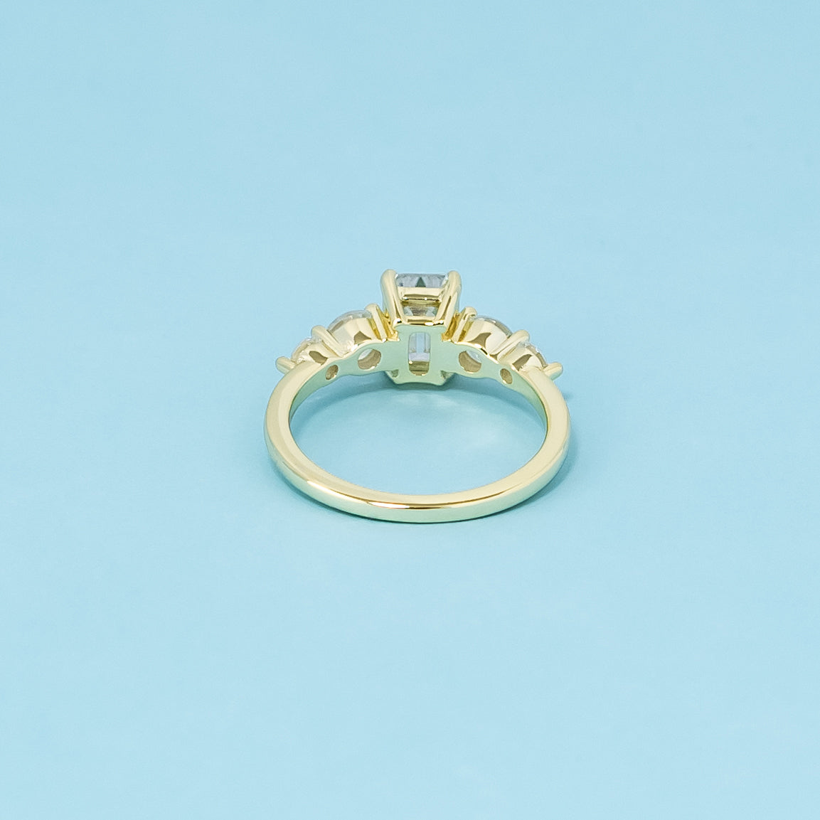 This 9ct yellow gold engagement ring features five brilliant emerald cut moissanites, representing everlasting elegance.