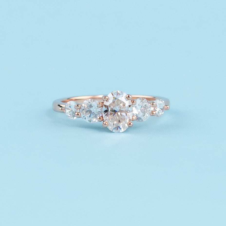 Stunning five-stone engagement ring featuring oval cut moissanites, set in warm 9ct rose gold for eternal brilliance.