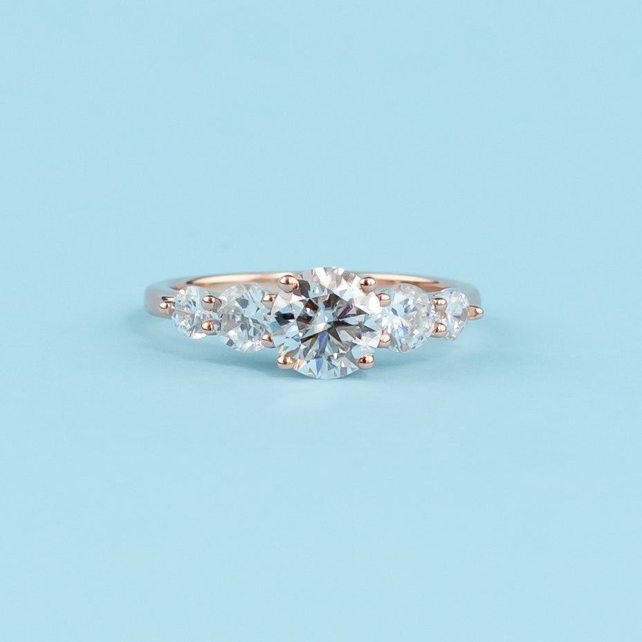 Stunning five-stone engagement ring featuring round brilliant moissanites, set in warm 9ct rose gold for eternal brilliance.