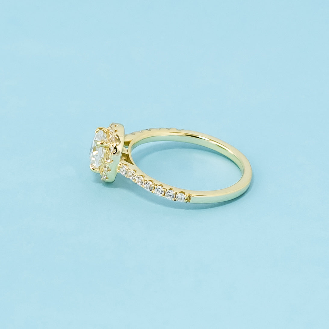 A beautiful halo design highlights the unique shape of a cushion cut moissanite in this 9ct yellow gold ring.