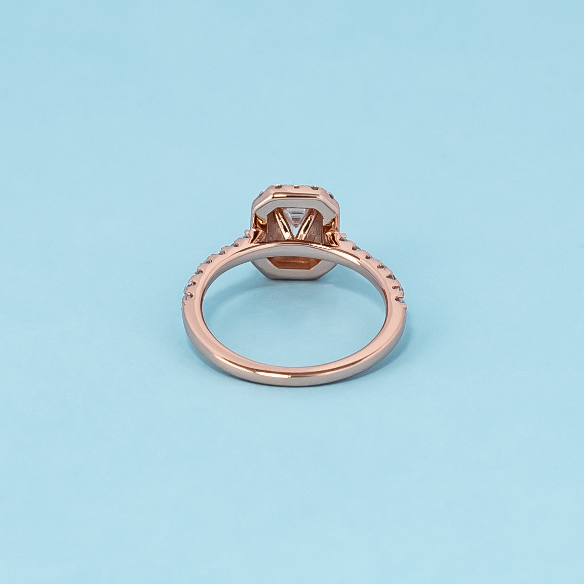Timeless and luxurious 9ct rose gold engagement ring showcasing a beautiful emerald cut moissanite with a classic halo design.