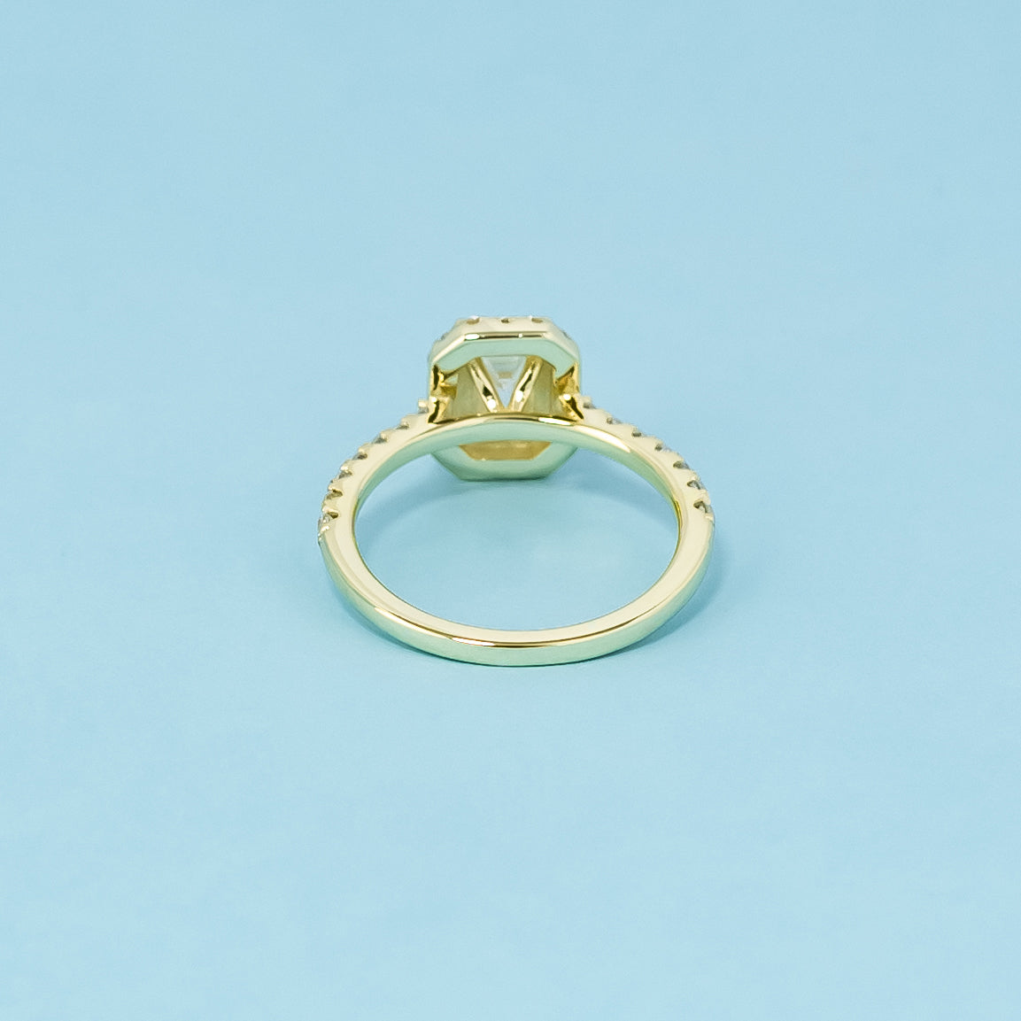 This elegant 9ct yellow gold ring features an emerald cut moissanite with a classic halo, perfect for a timeless engagement.