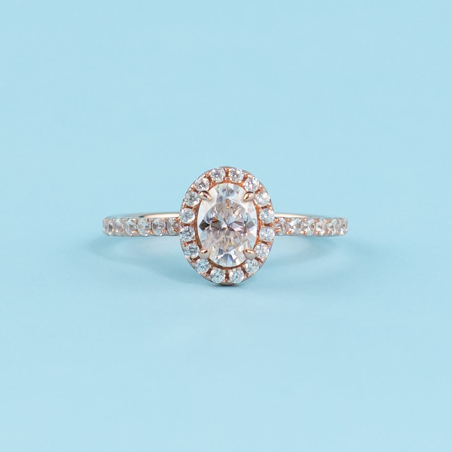 Elegant oval cut moissanite engagement ring with a classic halo setting, crafted in warm 9ct rose gold.