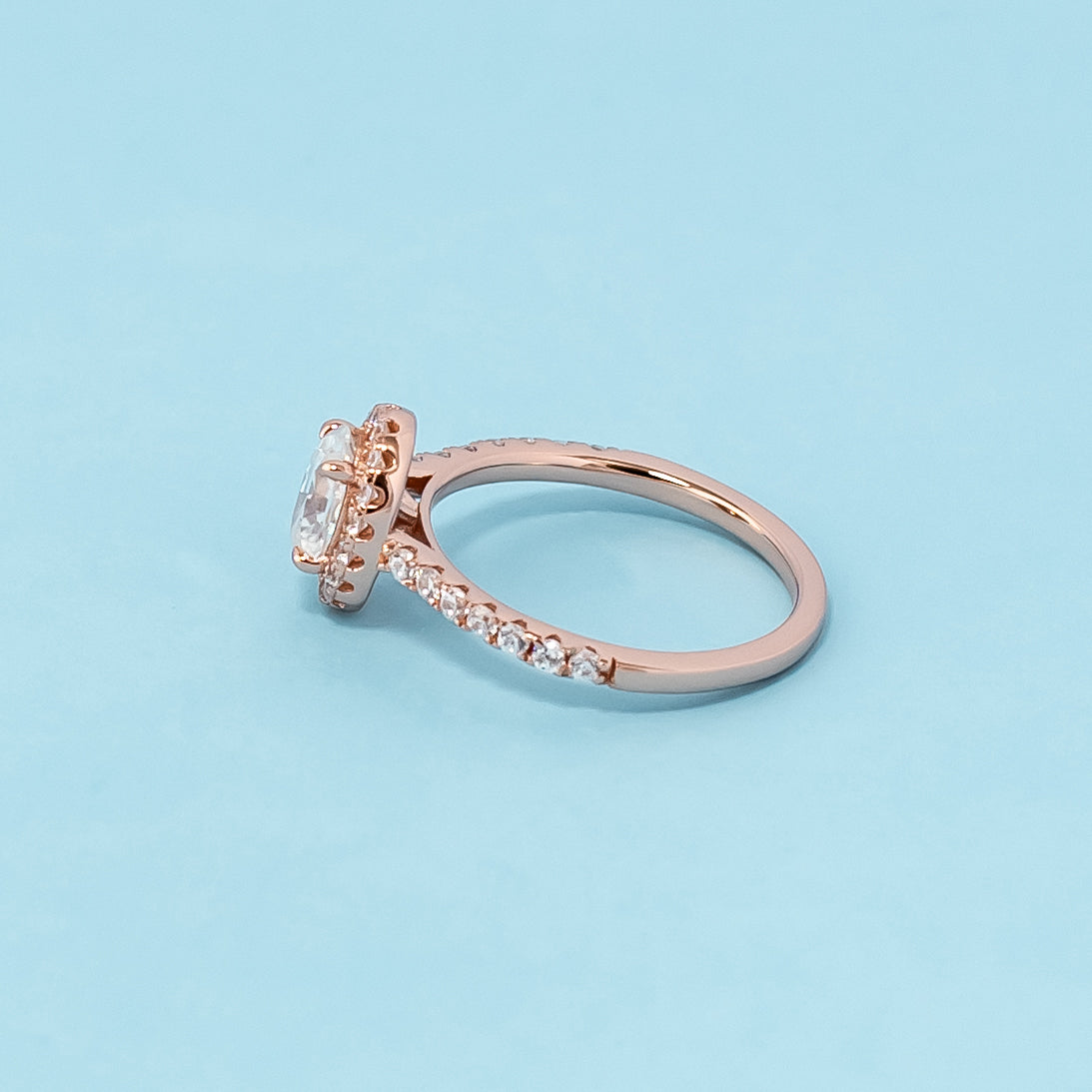 Stunning rose gold engagement ring featuring a sparkling oval cut moissanite surrounded by a dazzling halo.