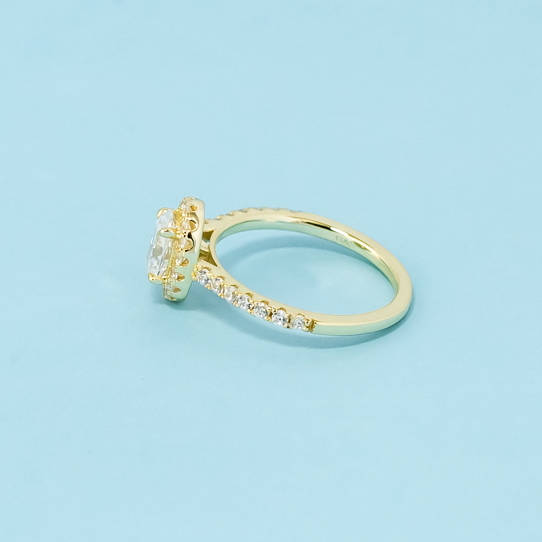 A beautiful halo design highlights the elegant shape of an oval cut moissanite in this 9ct yellow gold ring.