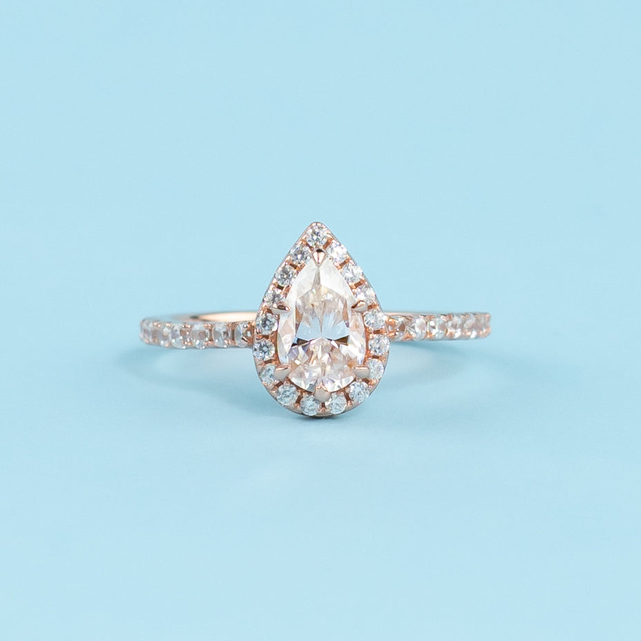 Elegant pear-shaped moissanite engagement ring with a classic halo setting in warm 9ct rose gold.