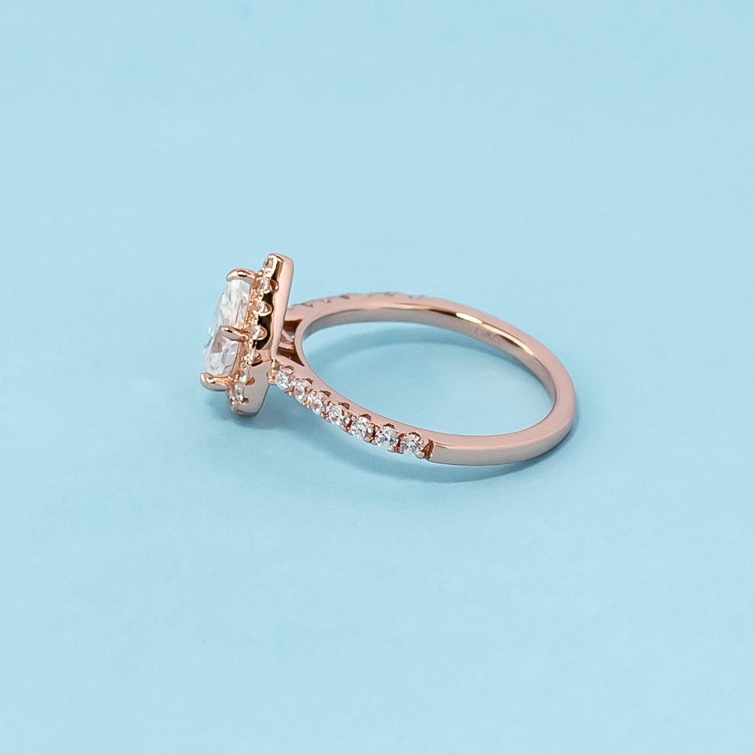 Stunning rose gold engagement ring showcasing a sparkling pear-shaped moissanite embraced by a dazzling halo.