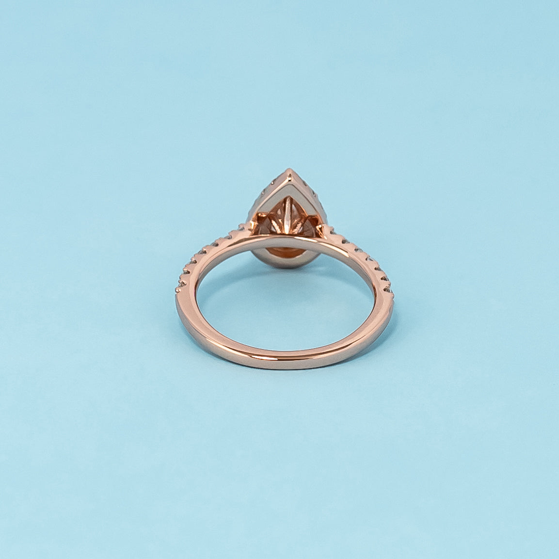 Timeless and luxurious 9ct rose gold engagement ring featuring a beautiful pear-shaped moissanite in a classic halo design.