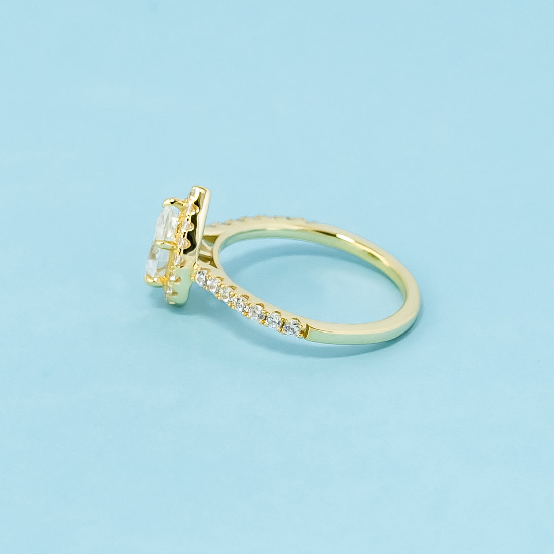 A beautiful halo design highlights the unique shape of a pear-shaped moissanite in this 9ct yellow gold ring.