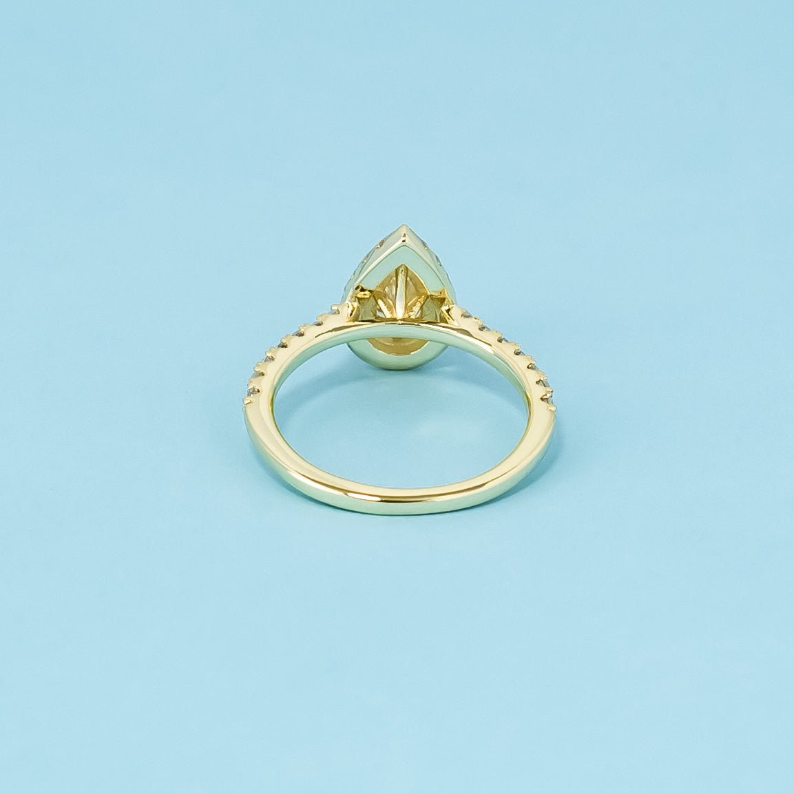 This elegant 9ct yellow gold ring features a pear-shaped moissanite with a classic halo, creating a beautiful and enduring engagement ring.