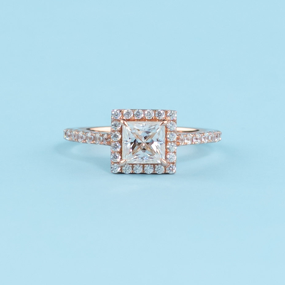 Elegant princess cut moissanite engagement ring with a classic halo setting, crafted in warm 9ct rose gold.