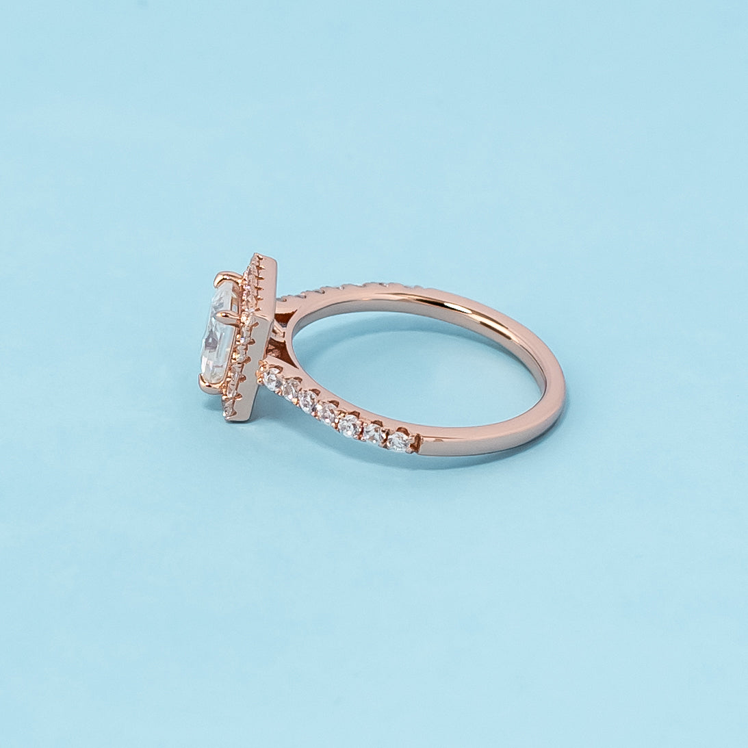 Stunning rose gold engagement ring featuring a sparkling princess cut moissanite surrounded by a dazzling halo.