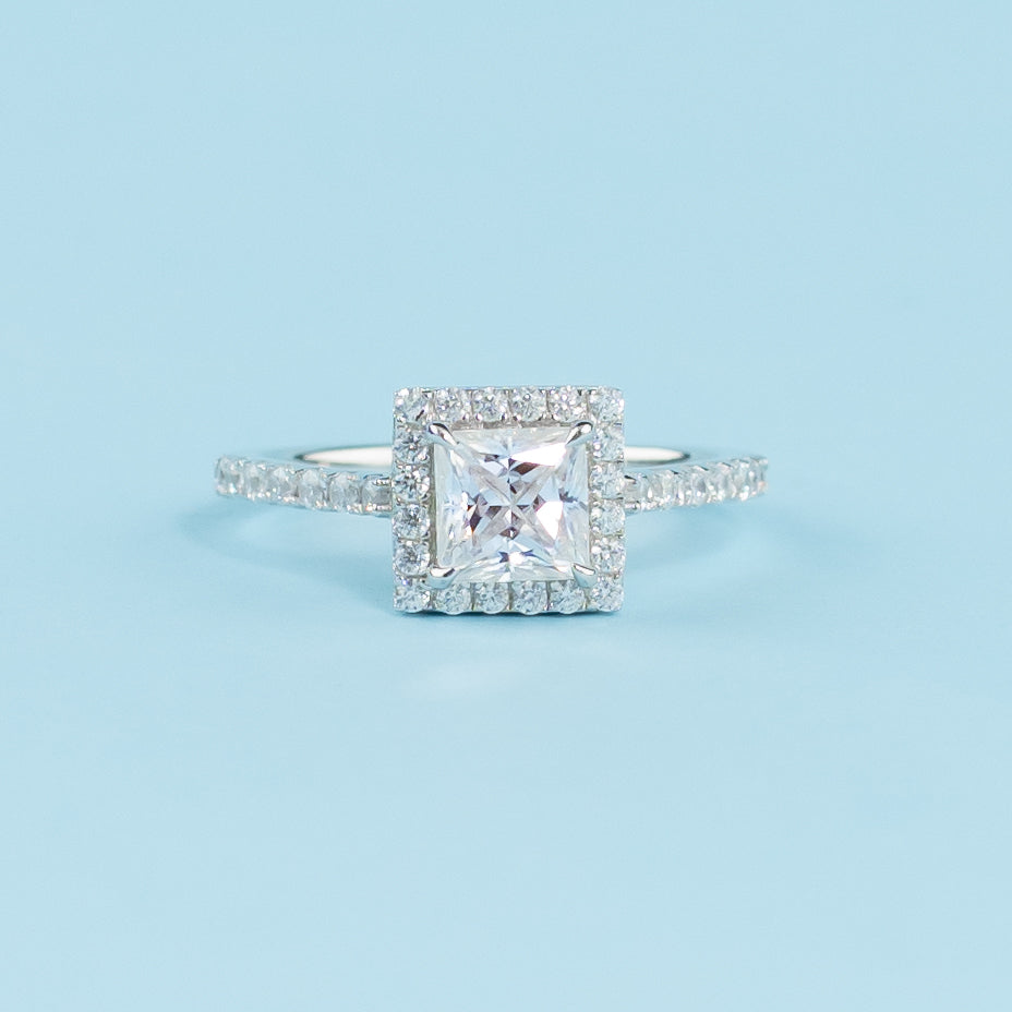 Elegant 9ct white gold engagement ring featuring a princess cut moissanite surrounded by a classic halo setting.