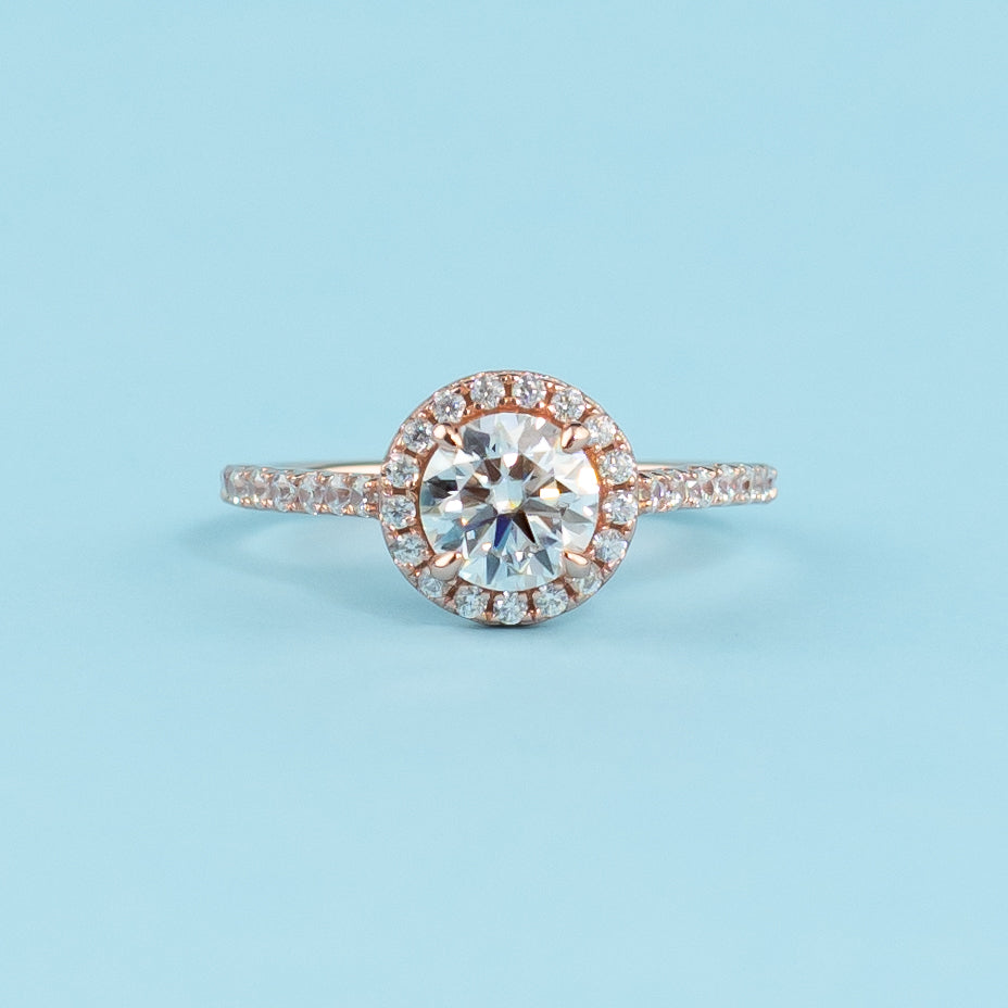 Elegant round brilliant moissanite engagement ring with a classic halo setting in warm 9ct rose gold.