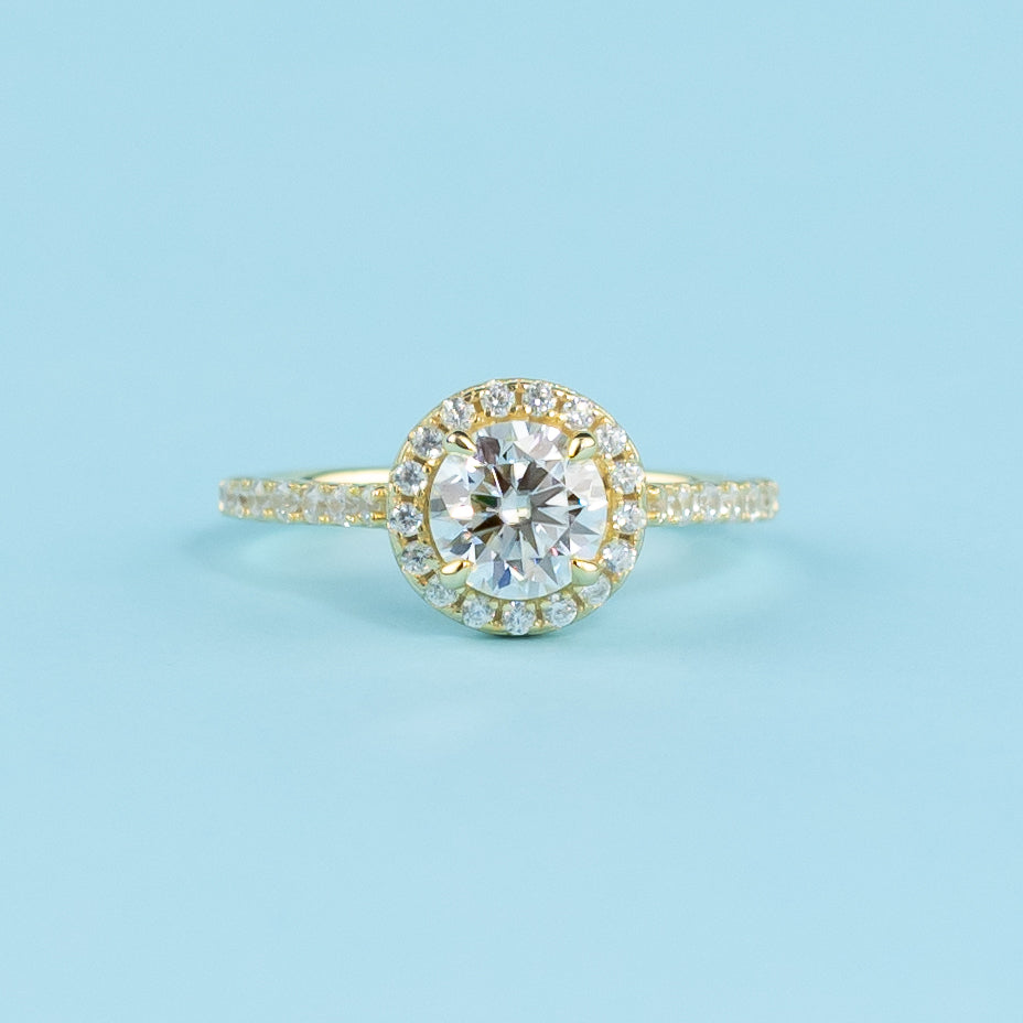 This ring showcases a brilliant round brilliant moissanite with a timeless halo setting in warm yellow gold.