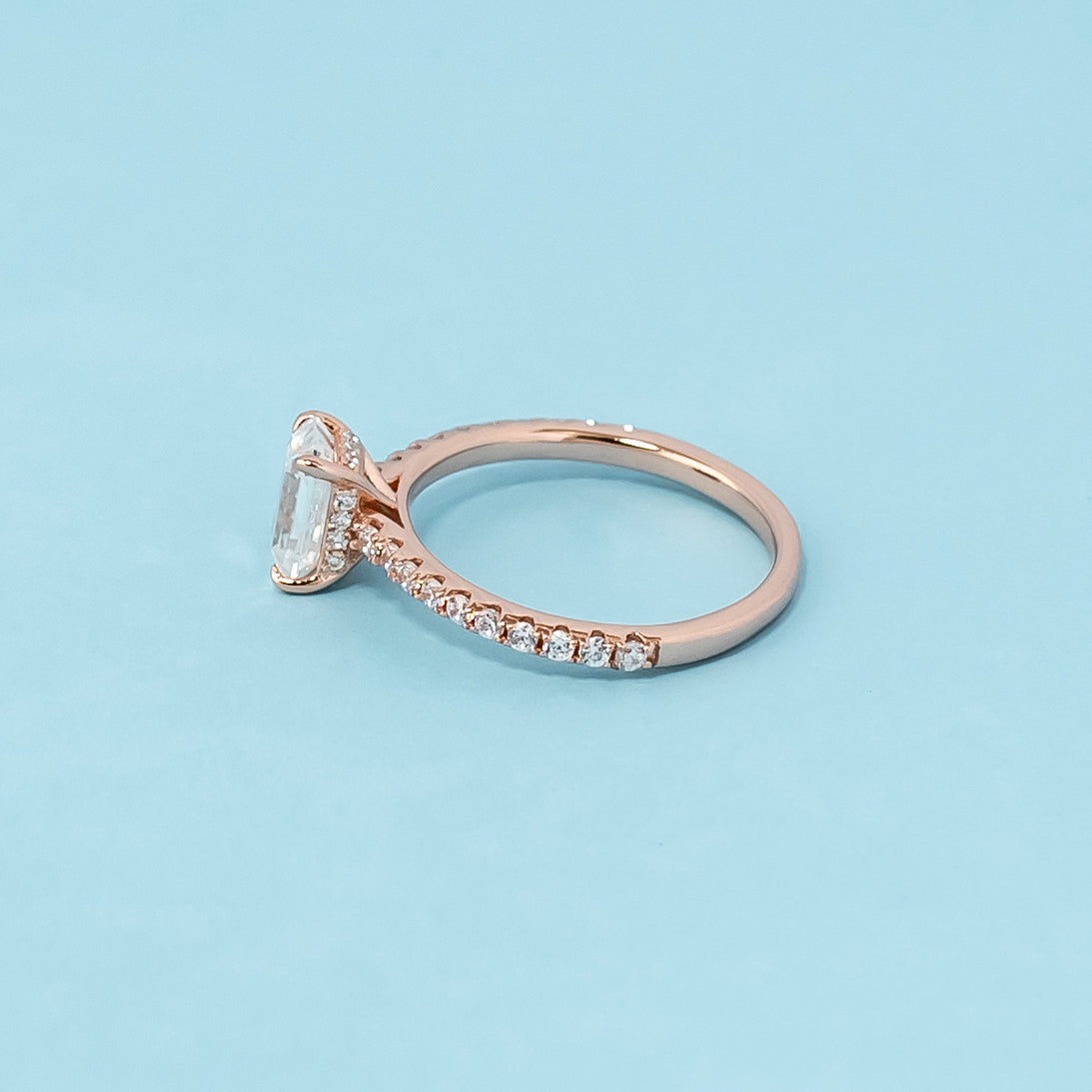 Stunning rose gold engagement ring featuring a sparkling emerald cut moissanite and a unique hidden design.