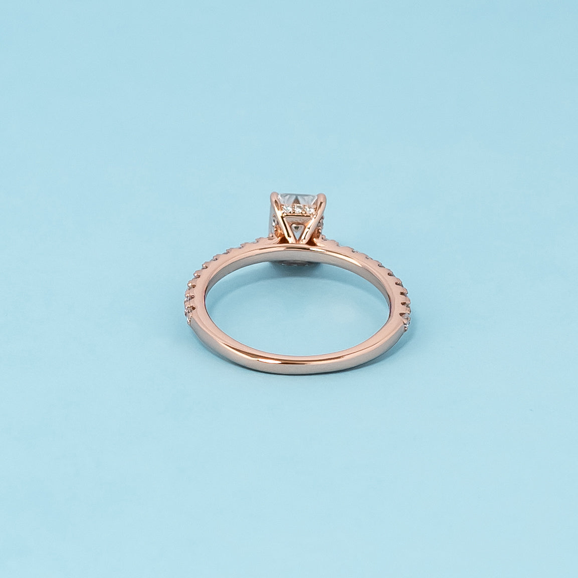 Luxurious 9ct rose gold engagement ring set showcasing a beautiful emerald cut moissanite with a subtle hidden halo.