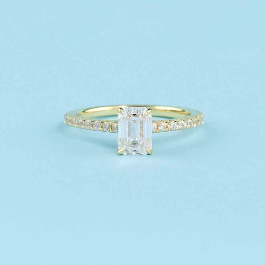 Showcasing a discreet hidden halo that enhances the sparkle of a beautiful emerald cut moissanite.