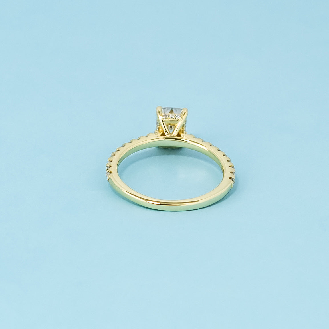 A sophisticated 9ct yellow gold engagement ring with a hidden halo for extra brilliance and a stunning emerald cut moissanite.