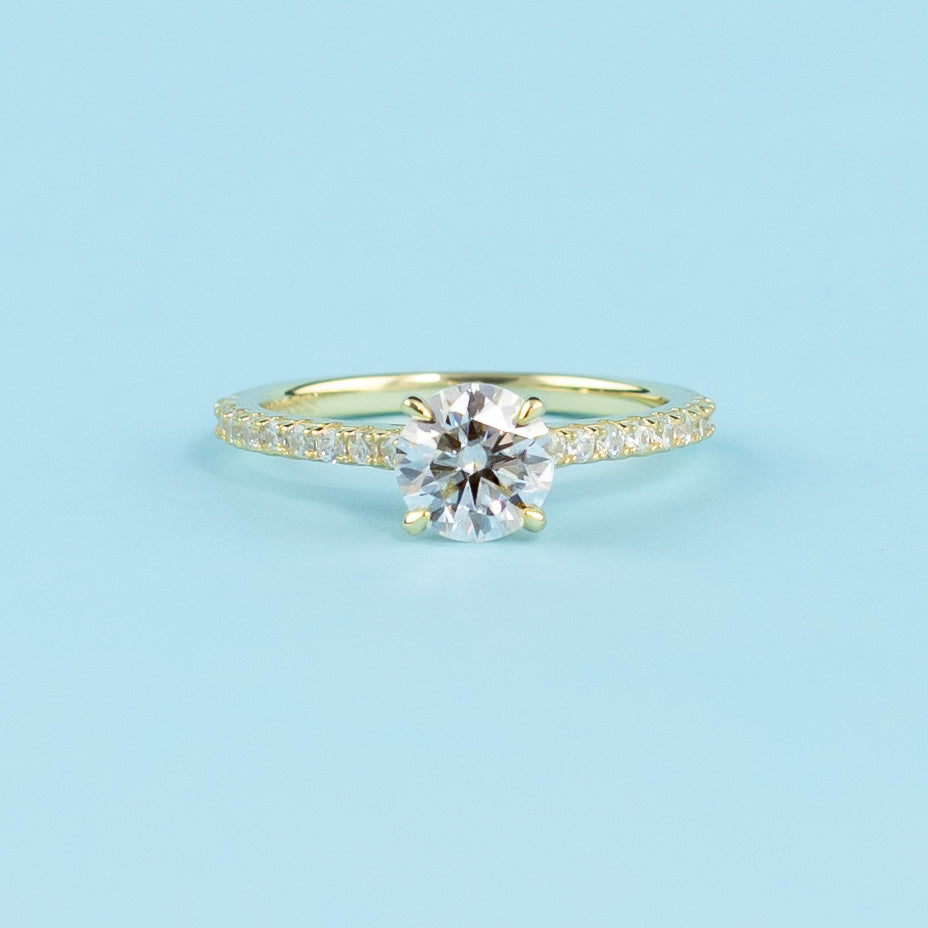 Showcases a beautiful round brilliant moissanite with a discreet hidden halo enhancing its brilliance.