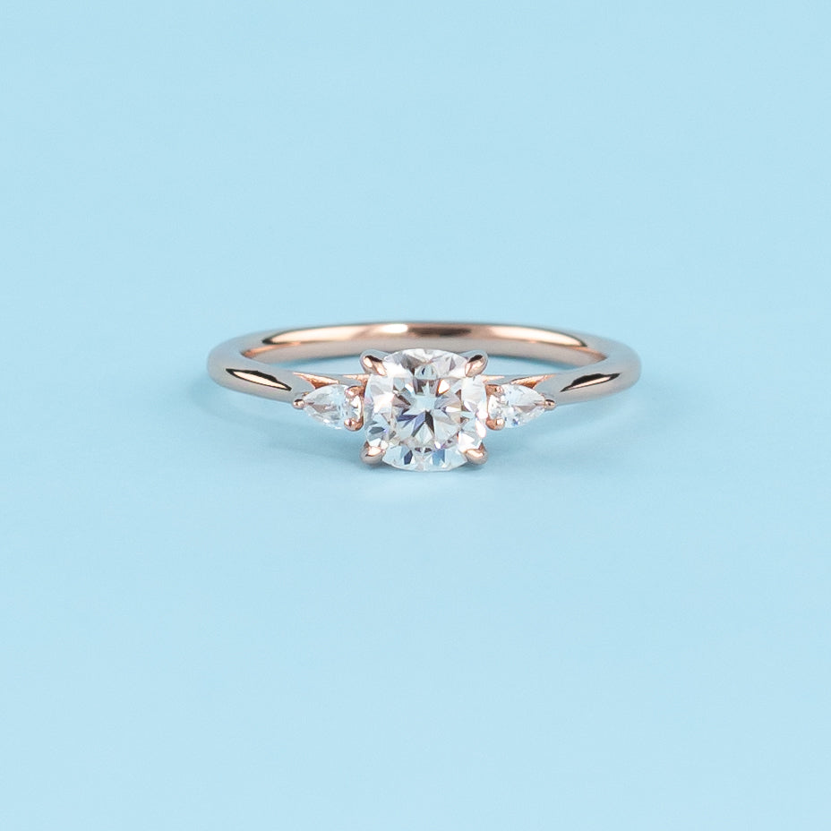 Stunning trilogy engagement ring with cushion cut moissanites, set in warm 9ct rose gold, symbolizing infinite love.