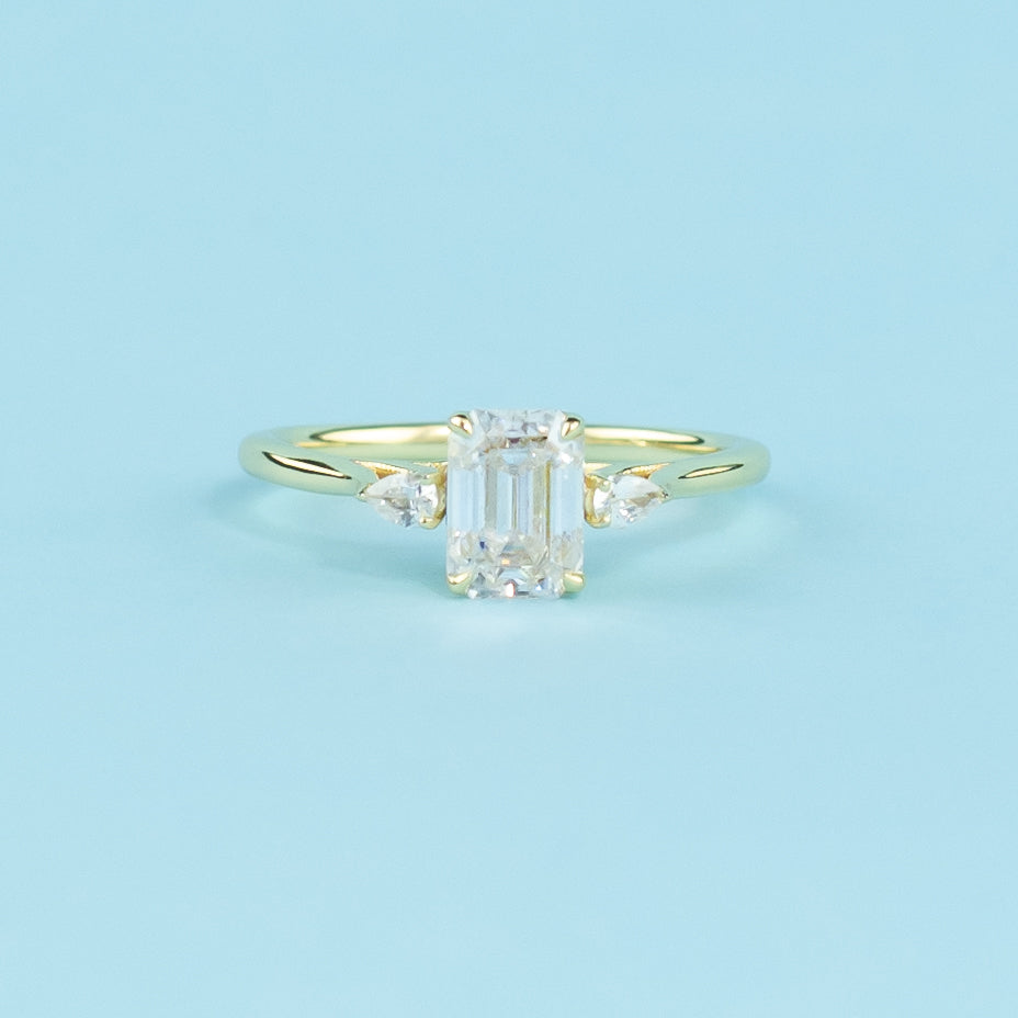 This elegant ring showcases three sparkling emerald cut moissanites in a warm 9ct yellow gold setting.