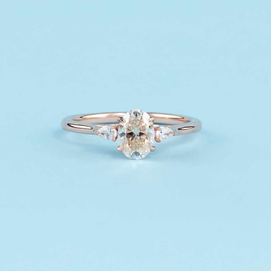 Stunning trilogy engagement ring with oval cut moissanites, set in warm 9ct rose gold, symbolizing infinite love.