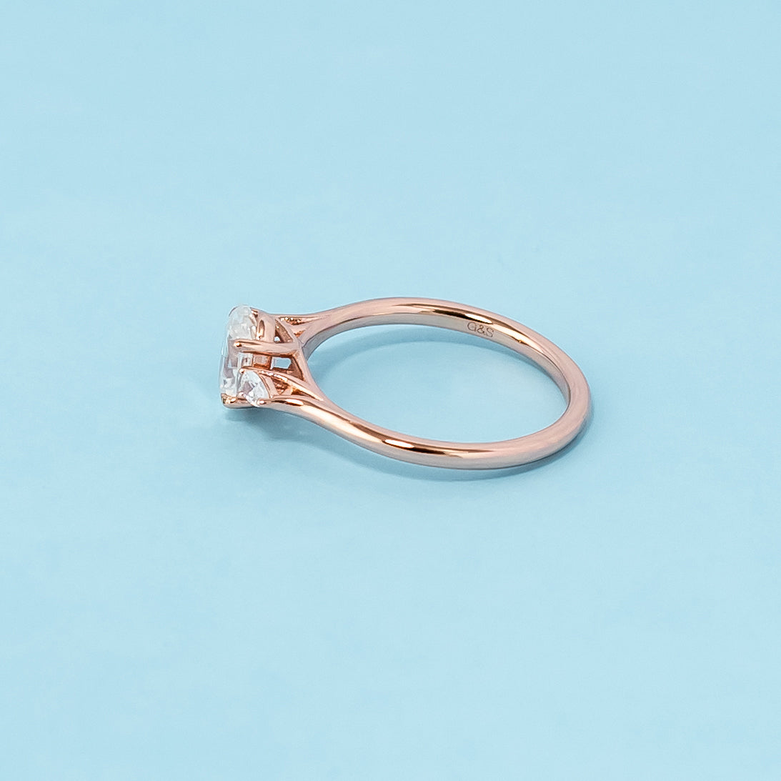 Elegant rose gold engagement ring showcasing three sparkling oval cut moissanites in a classic trilogy design.