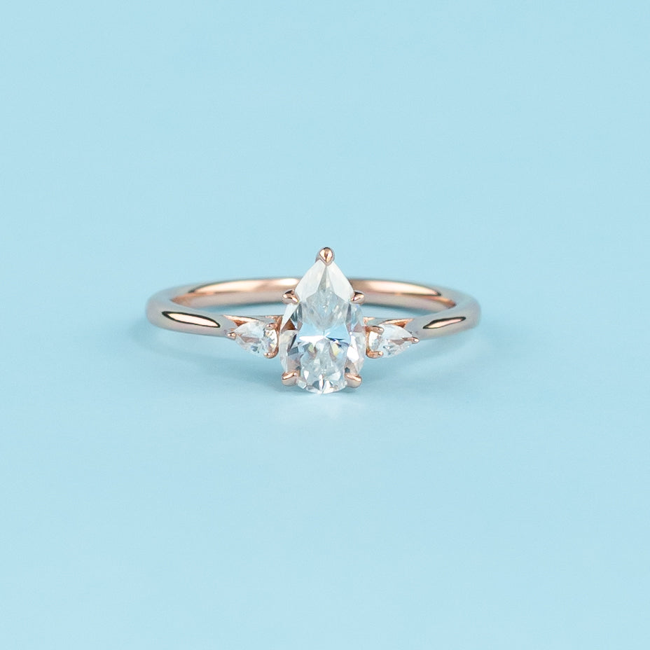 Stunning trilogy engagement ring with pear-shaped moissanites, set in warm 9ct rose gold, symbolizing infinite love.