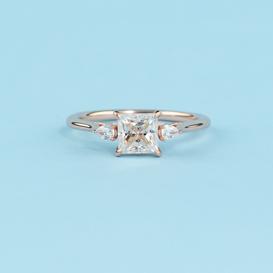 Stunning trilogy engagement ring with princess cut moissanites, set in warm 9ct rose gold, representing infinite love.