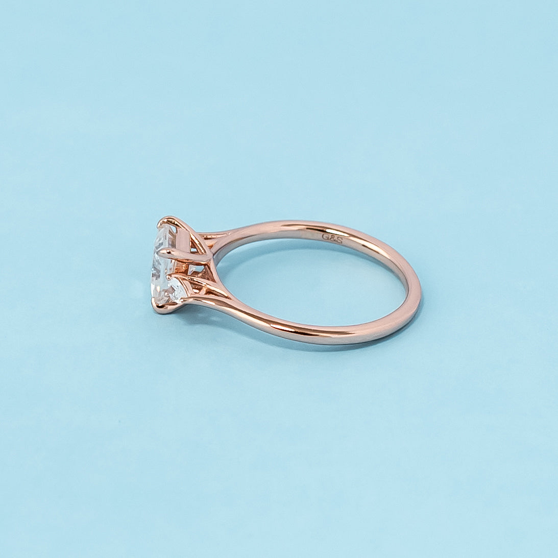 Elegant rose gold engagement ring featuring three sparkling princess cut moissanites in a classic trilogy design.