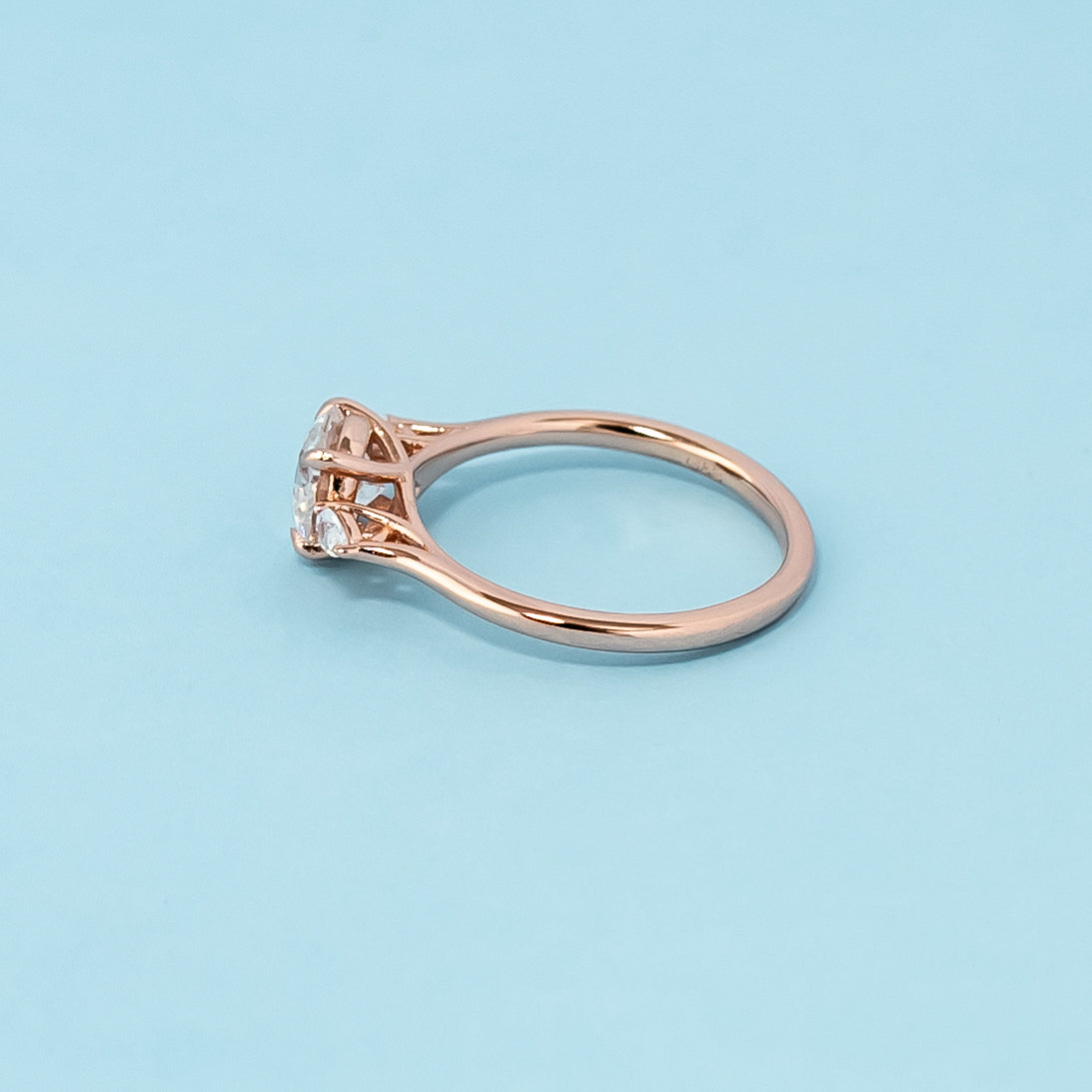 Elegant rose gold engagement ring showcasing three sparkling round brilliant moissanites in a classic trilogy design.