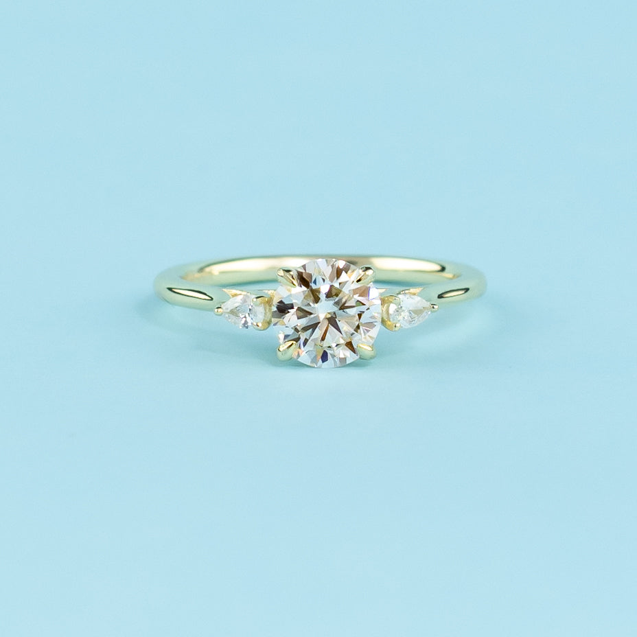 Showcases three sparkling round brilliant moissanites set in a warm 9ct yellow gold band, representing your eternal love.