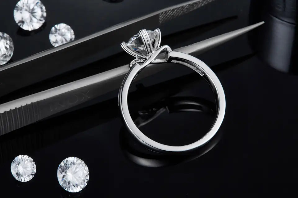 A sophisticated engagement ring featuring a dazzling 1.00ct moissanite solitaire and a polished sterling silver band with an interwoven infinity design.